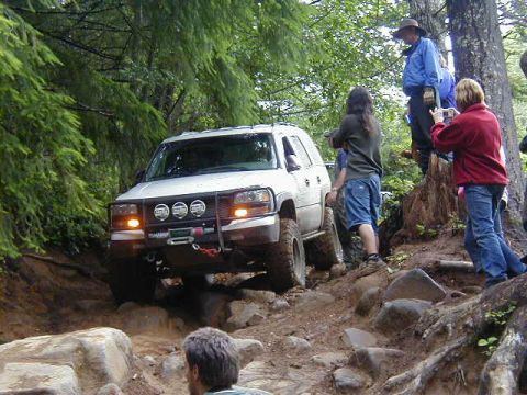 1994 Ford Explorer - A white 1994 Ford Explorer navigates a challenging rocky off-road course with spectators watching.