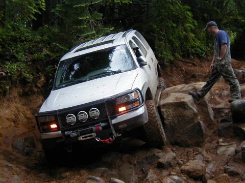 1994 Ford Explorer - A white SUV tackles a challenging off-road course, demonstrating its capability on rough terrain.