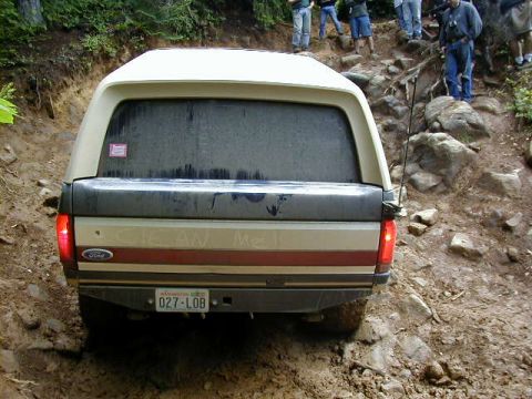 1994 Ford Explorer - This Ford pickup truck, equipped with a camper shell, navigates a challenging off-road terrain.