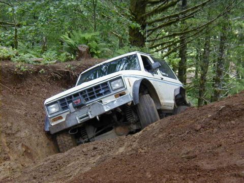 1994 Ford Explorer - This off-road SUV is captured mid-climb on a challenging dirt path in a wooded area.