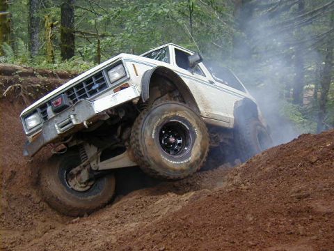 1994 Ford Explorer - Modified truck navigates a challenging off-road trail in a wooded area.