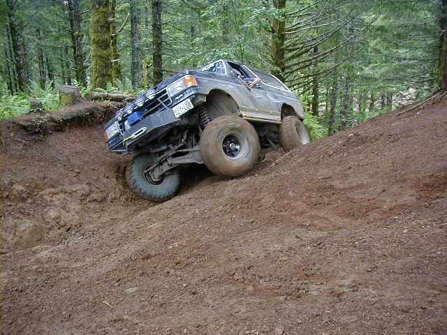 Dark 1994 Ford Explorer climbing steep dirt hill, front 3/4 view