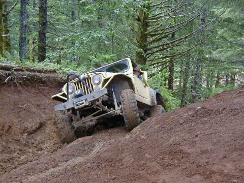 1994 Ford Explorer - A yellow Jeep CJ-7 navigates a challenging off-road trail through a wooded area.