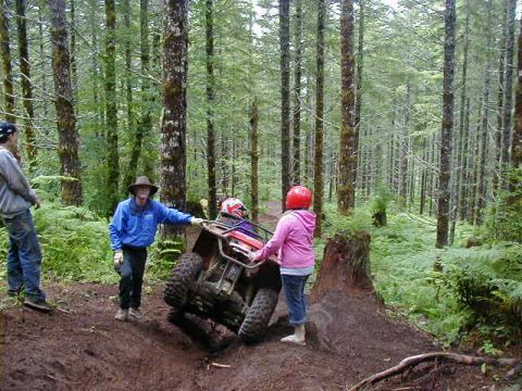 1994 Ford Explorer - People interact with an all-terrain vehicle on a dirt path surrounded by trees.