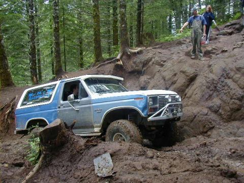 1994 Ford Explorer - This Ford Bronco is tackling a challenging off-road course, with onlookers observing from the trail above.