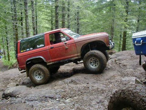 1994 Ford Explorer - A red 1989 Ford Bronco II navigates a challenging off-road course through a forest.