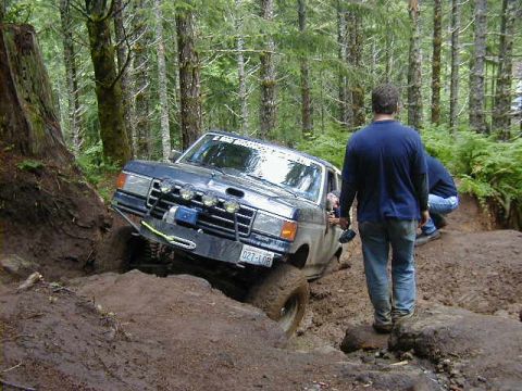 1994 Ford Explorer - Ford Bronco navigating a muddy off-road trail in a forest setting.