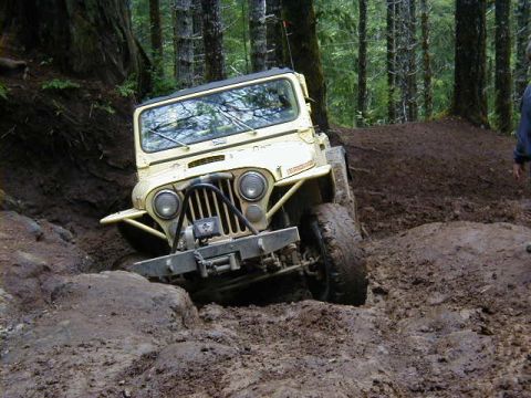 1994 Ford Explorer - A yellow Jeep navigates a challenging muddy terrain during an off-road excursion.