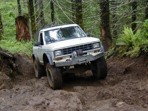 1994 Ford Explorer - This off-road SUV navigates a challenging muddy terrain in a wooded area.