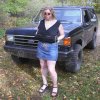 1989 Ford Bronco - A woman stands in front of a black SUV with a distinctive grille and square headlights.