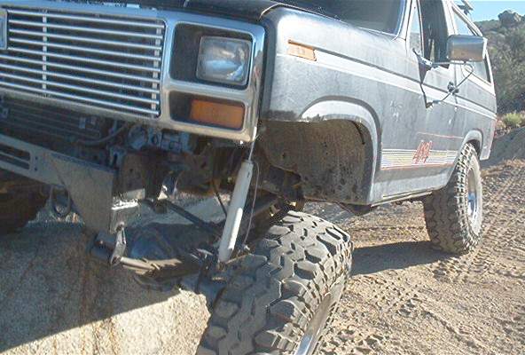 Dark 1980s Ford Bronco 4x4 with off-road tires on rocky terrain