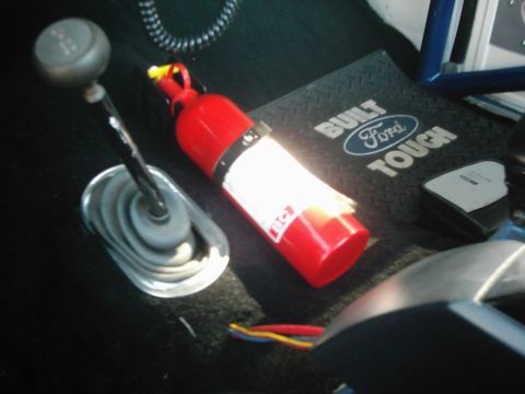 1978 Ford Bronco - Interior view of a vehicle shows a fire extinguisher and a gear shift lever on a floor mat.