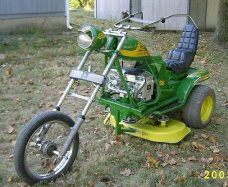 1990 Ford Bronco - custom chopper-style machine built from a green John Deere riding mower with a long front fork sits on a lawn.