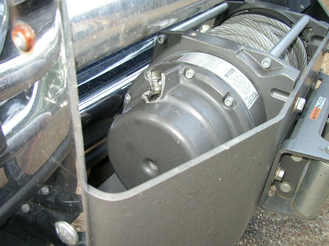 Winch with steel cable mounted on a vehicle's front end, chrome bumper visible