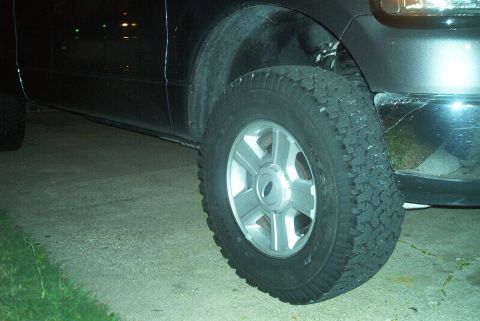 1986 Ford Bronco - Close-up of the front wheel and fender of a black Ford F-150 truck.