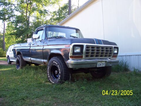 1987 Ford Bronco - This Ford F-150 pickup truck is parked next to a white van in a grassy area.
