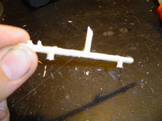 Hand holding a plastic model sprue with several small parts attached