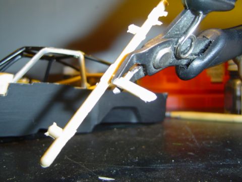 1979 Ford Bronco - A model car part is being trimmed with pliers, showing the detail of the model's construction.