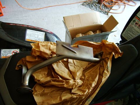 2003 Ford Mustang - A new oil pump pickup tube is shown, partially wrapped in brown paper, next to an open cardboard box.