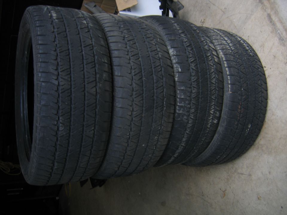 Row of four used tires lying on a concrete floor