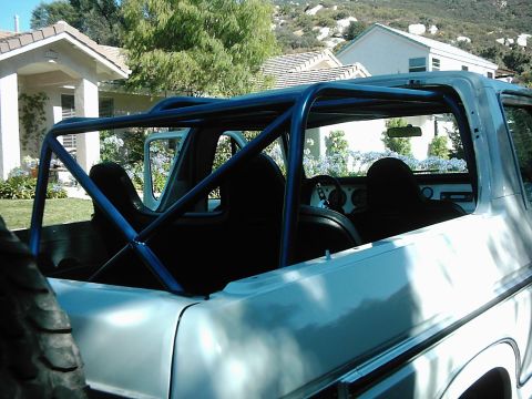 1978 Ford Bronco - The interior of a classic SUV is shown with a prominent blue roll cage installed.