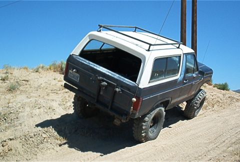 1986 Ford Bronco - Ford Bronco navigates a sandy incline under a clear blue sky.