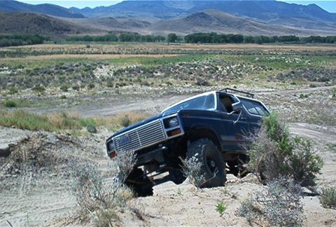 1986 Ford Bronco - This 1980s Ford Bronco navigates challenging terrain in a scenic, arid environment.