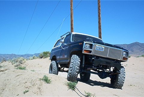 1986 Ford Bronco - Modified 1986 Ford Bronco tackling off-road terrain on a sunny day.