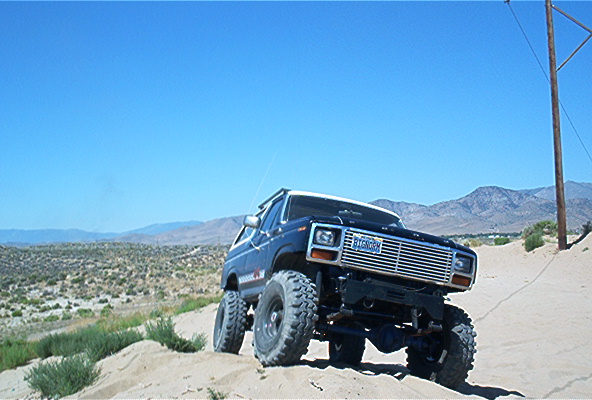 Lifted 1986 Ford Bronco with chrome grille and off-road tires on sand