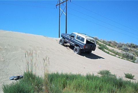 1986 Ford Bronco - This 1986 Ford Bronco navigates a sandy incline under a clear blue sky.