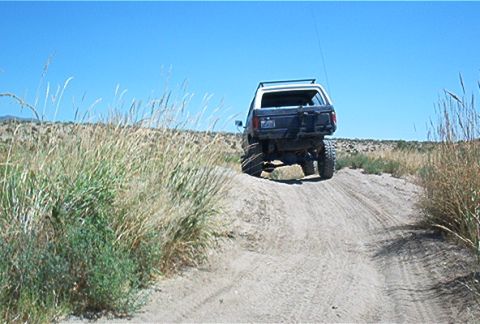 1986 Ford Bronco - A Ford Bronco navigates a sandy incline on a clear day.