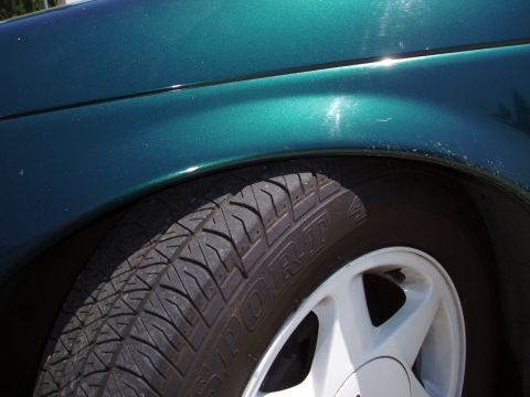 1993 Ford Taurus - Front wheel well detail of a 1993 Ford Taurus, a white five-spoke wheel and tire.