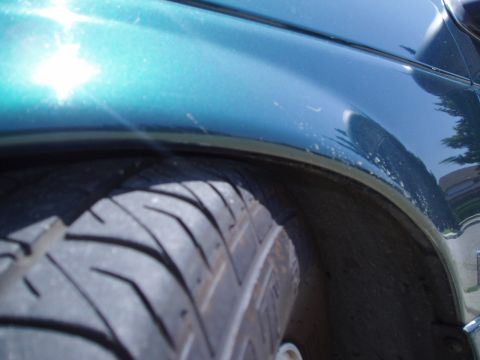 1993 Ford Taurus - A close-up view of a vehicle's wheel well and fender shows the tire and the car's teal paint.
