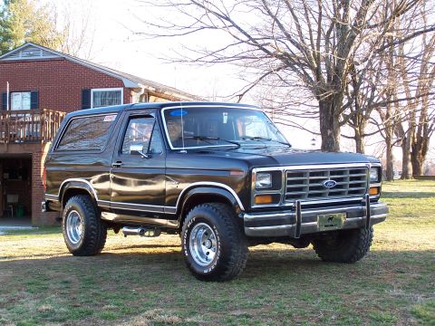 1983 Ford Bronco - This black Ford Bronco, likely from the early 1980s, is shown from a three-quarter front angle on a grassy lawn.