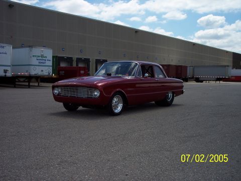1960 Ford Falcon - Maroon 1960 Ford Falcon two-door sedan with aftermarket wheels parked outside a warehouse.