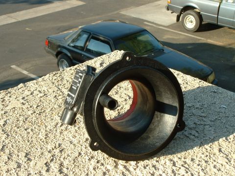1992 Ford Crown Victoria - A car part sits on a textured surface with two vehicles in the background.