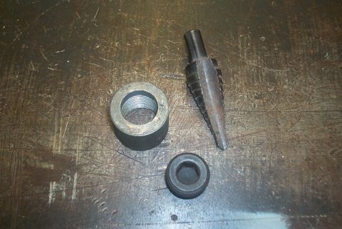 1983 Ford Bronco - A stepped reamer tool, a threaded adapter, and a rubber seal are laid out on a workbench.
