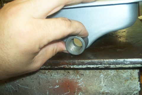 1983 Ford Bronco - Close-up of a hand holding a metal part with a threaded fitting.