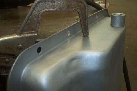 1983 Ford Bronco - A metal part, possibly an oil pan, is held by a clamp with a socket resting on it.