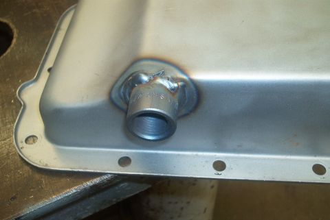 1983 Ford Bronco - A metal pan with a drain plug that has been welded in place, showing signs of recent work.