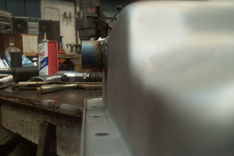 1983 Ford Bronco - A metal part with a welded flange sits on a workbench next to tools and a can of Magic cleaner.