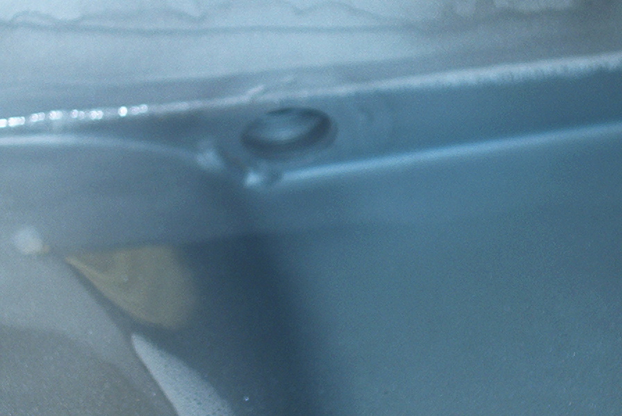 Drain plug hole on blue metal surface