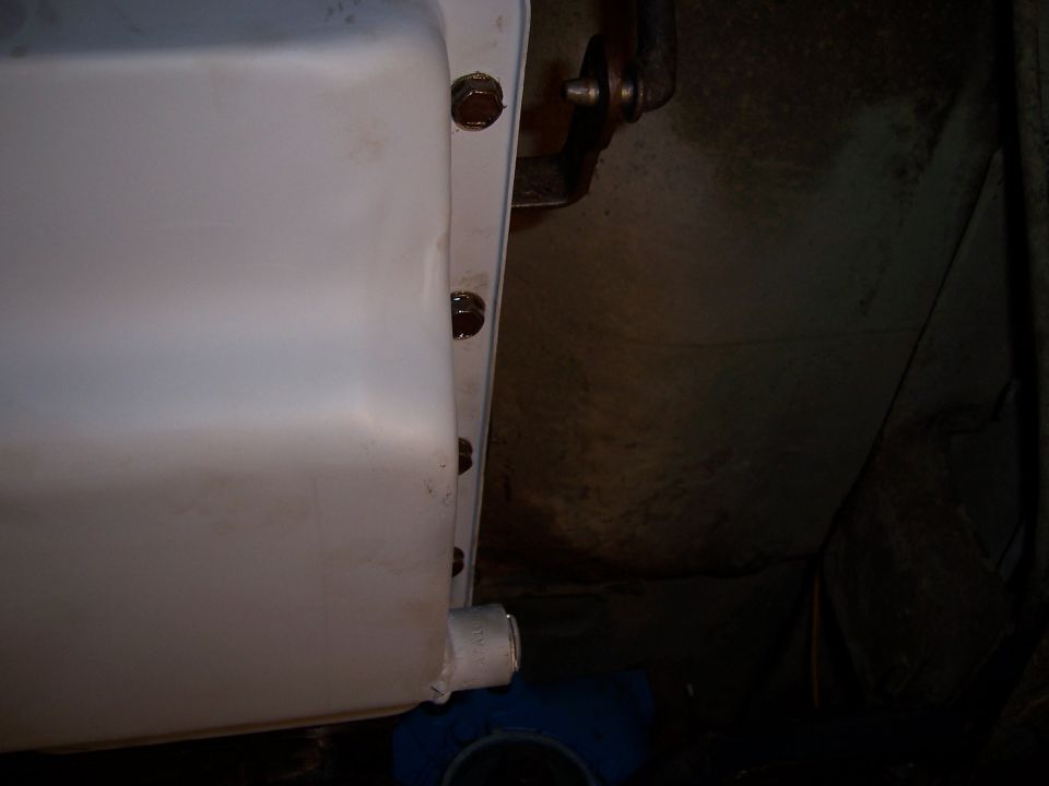 Close-up of an oil pan with bolts visible, showing the drain plug area