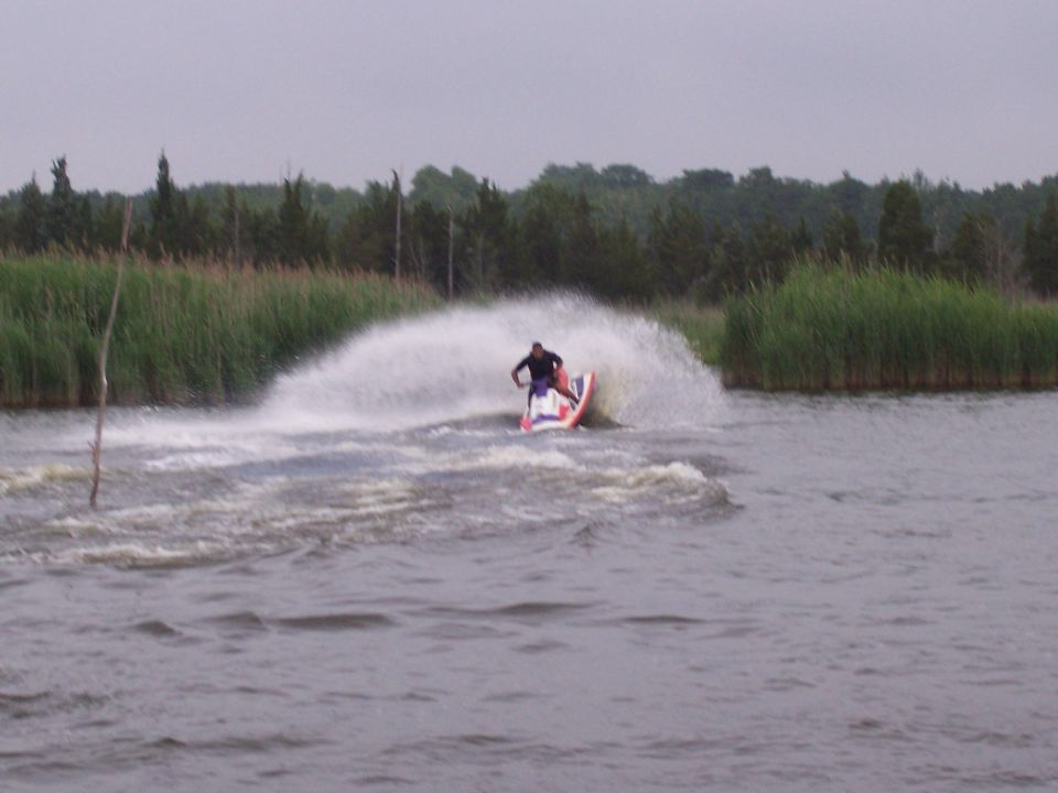 Rider on standup jet ski carving a turn with big water spray on a lake