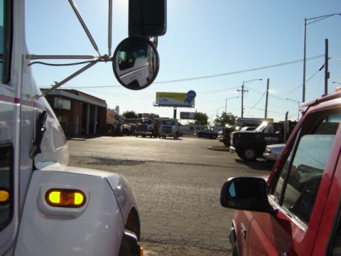1992 Ford Bronco - A variety of trucks and SUVs are visible in a parking lot scene, with a billboard in the background.