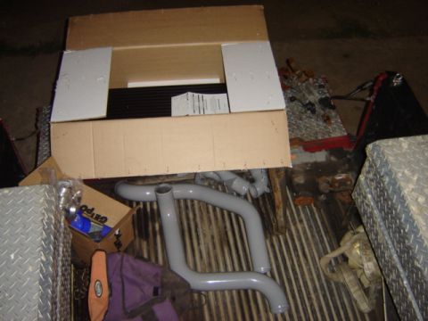 1992 Ford Bronco - Gray exhaust pipes and a cardboard box containing parts are visible in the bed of a truck.