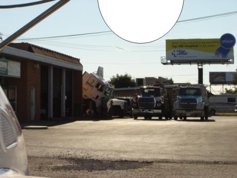 1992 Ford Bronco - Several trucks are parked outside a building, with one armored vehicle in a precarious position.