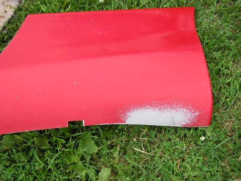 1994 Ford Probe - A red car door is shown lying on grass, with primer visible on the lower right section.