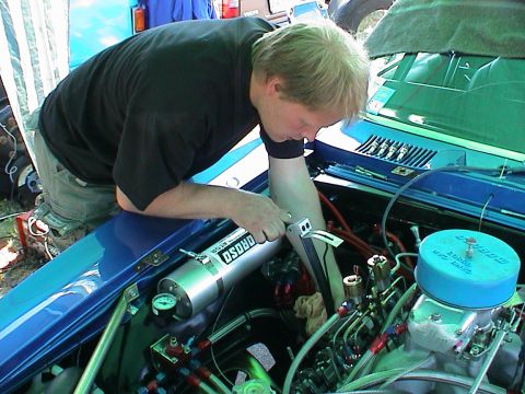 1979 Ford Bronco - Mechanic works on a custom engine, possibly a race car, with various hoses and components visible.