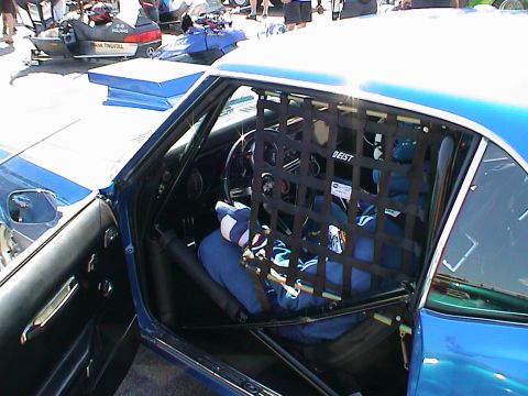 1979 Ford Bronco - Race car interior with safety net and driver wearing a blue suit.